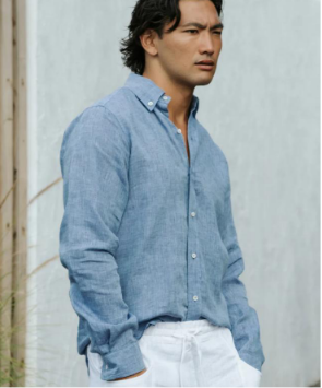 Front view of a man showcasing a classic light blue chambray 100% pure linen casual long-sleeve button-up shirt paired with white trousers.