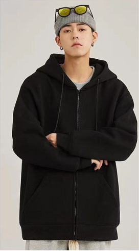 Front view of a young man showcasing a cozy solid black zip-up hooded jacket with soft white drawstrings paired with a beanie.